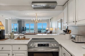 Una cocina moderna con una isla central, electrodomésticos de acero inoxidable y vistas al océano.