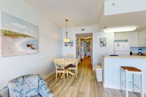 Una cucina moderna con mobili bianchi, un tavolo da pranzo in legno e un angolo bar.