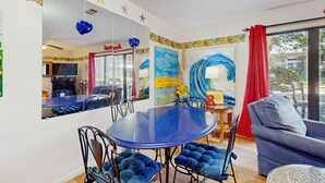 A dining area with a round table, blue upholstered chairs, a sofa, and a large mirror reflecting the room. - Cute ground floor condo with shared pool, access to shuffleboard and tennis (Santa Rosa Beach)