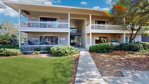 A two-story building with a central walkway, balconies, and a small garden area. - Cute ground floor condo with shared pool, access to shuffleboard and tennis (Santa Rosa Beach)