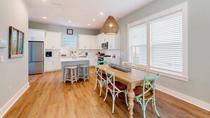 Una cocina moderna con armarios blancos, una mesa de comedor de madera y sillas color turquesa.