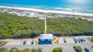 Vista aérea de una zona costera con un estacionamiento, un edificio de techo azul y una playa al fondo.
