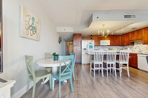 A modern kitchen with wooden cabinets, a white refrigerator, and a marble countertop. - Beachview Condo with full kitchen, shared pool and beach access (Panama City Beach)