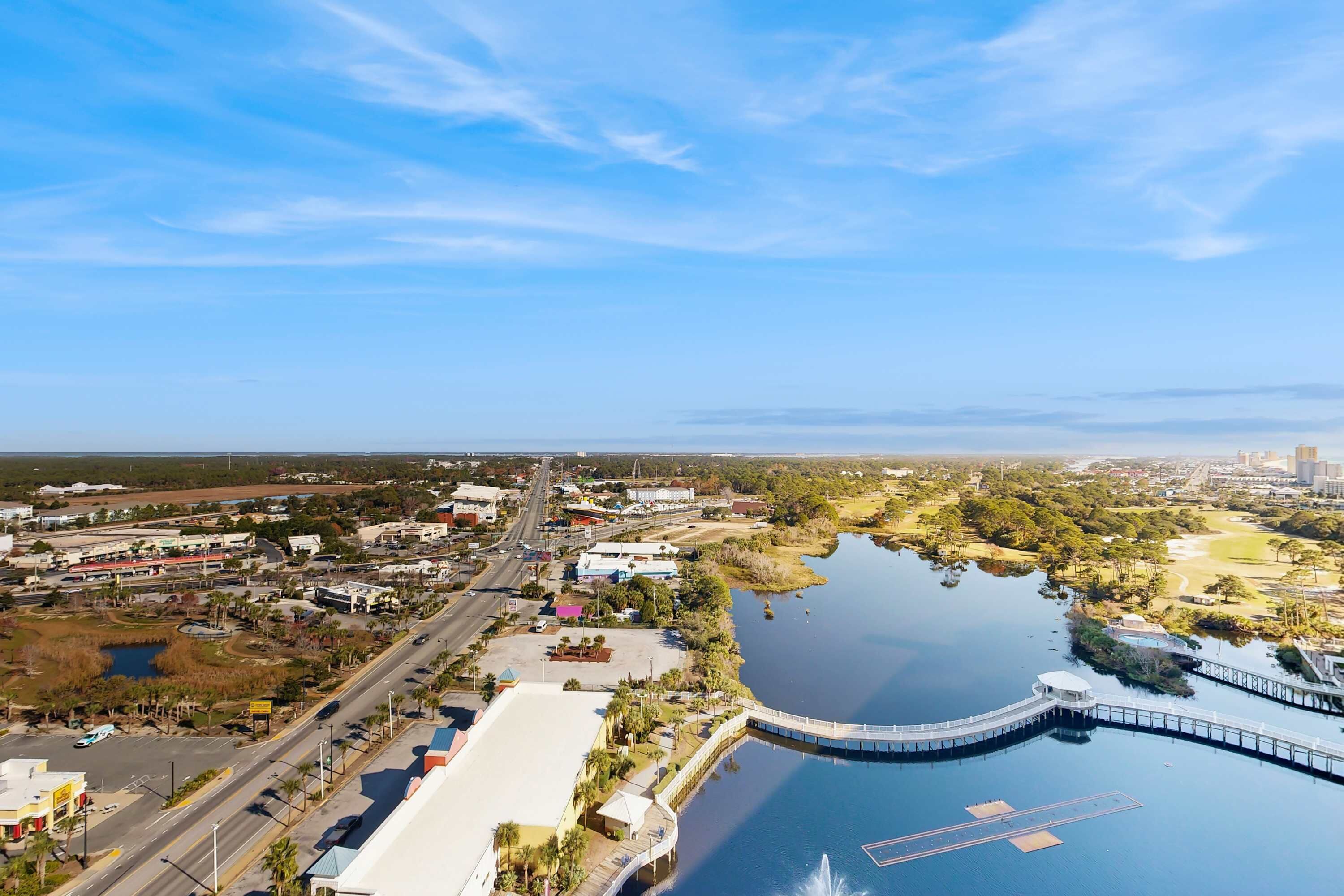 Vue aérienne d’une ville côtière avec un port de plaisance, un pont et un mélange de bâtiments commerciaux et résidentiels.