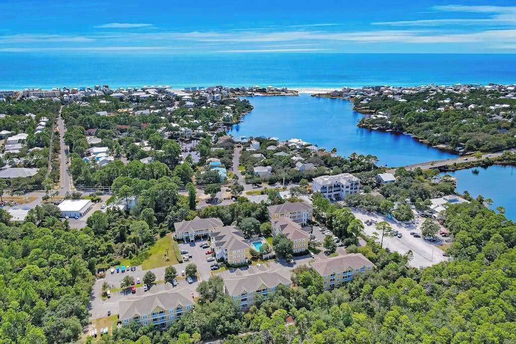 An aerial view of a coastal residential area with houses, a marina, and a large body of water.