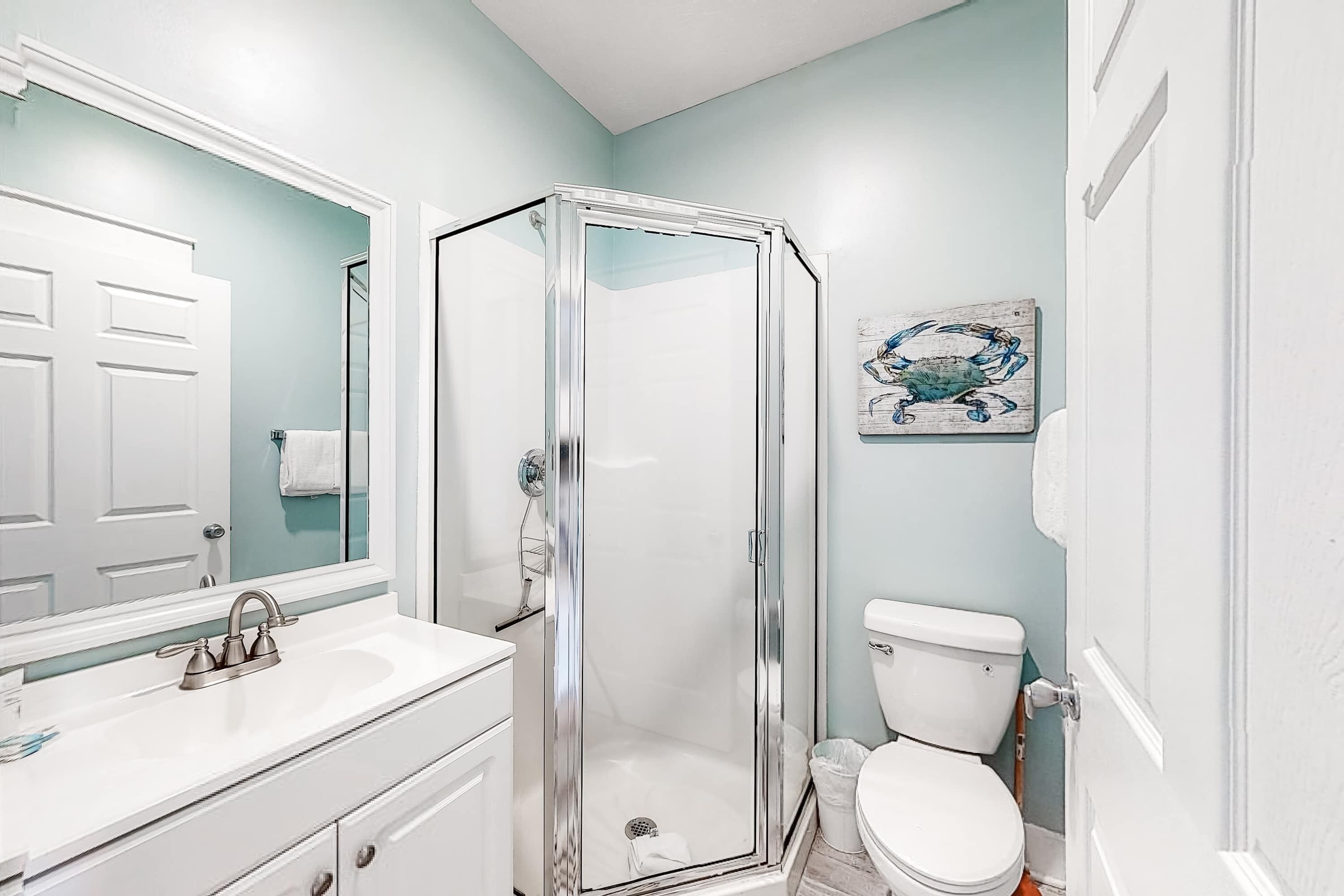 A bathroom with a glass-enclosed shower, a white sink, and a toilet.