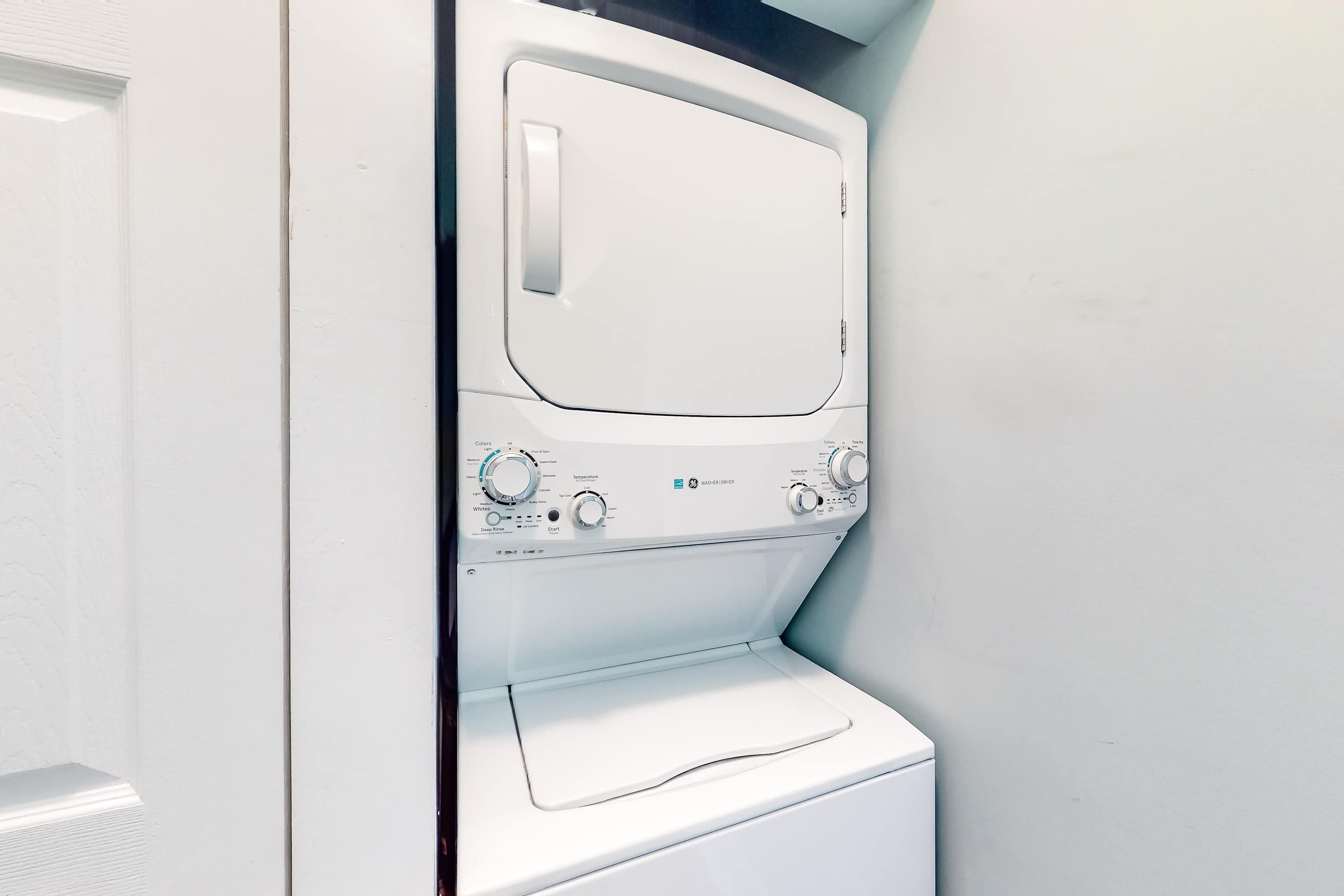A white washing machine with control knobs and a door, installed in a corner of a room.