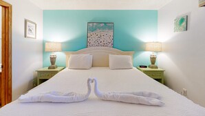 Una habitación de hotel con cama, dos mesitas de noche, dos lámparas y un cuadro en la pared.