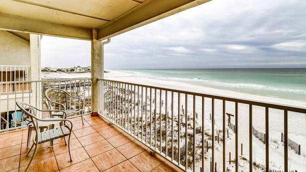 Un balcone con vista sulla spiaggia, dotato di ringhiera e due sedie.