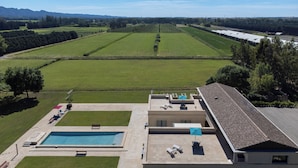 A modern building with a swimming pool, outdoor seating, and a view of a green field and distant mountains. - THE INTIMACY OF A PROVENCE ESTATE LA SUITE EUCALYPTUS 5 EPIS (Mollégès)