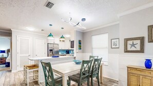 A modern kitchen with white cabinets, a central island, and green chairs. - Luxury home with private saltwater pool, spa, gazebo & deck - walk to beach (Santa Rosa Beach)