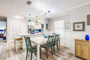 A modern kitchen with white cabinets, a central island, and green chairs. - Luxury home with private saltwater pool, spa, gazebo & deck - walk to beach (Santa Rosa Beach)