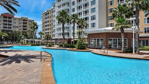 A hotel with a swimming pool, palm trees, and a brick building. - Luxurious bayfront condo in a gated resort with an amazing pool & hot tub (Panama City Beach)