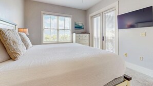 A bedroom with a large bed, a dresser, a TV, and a window with blinds. - Polished condo with balcony & pools - one block from the beach (Santa Rosa Beach)