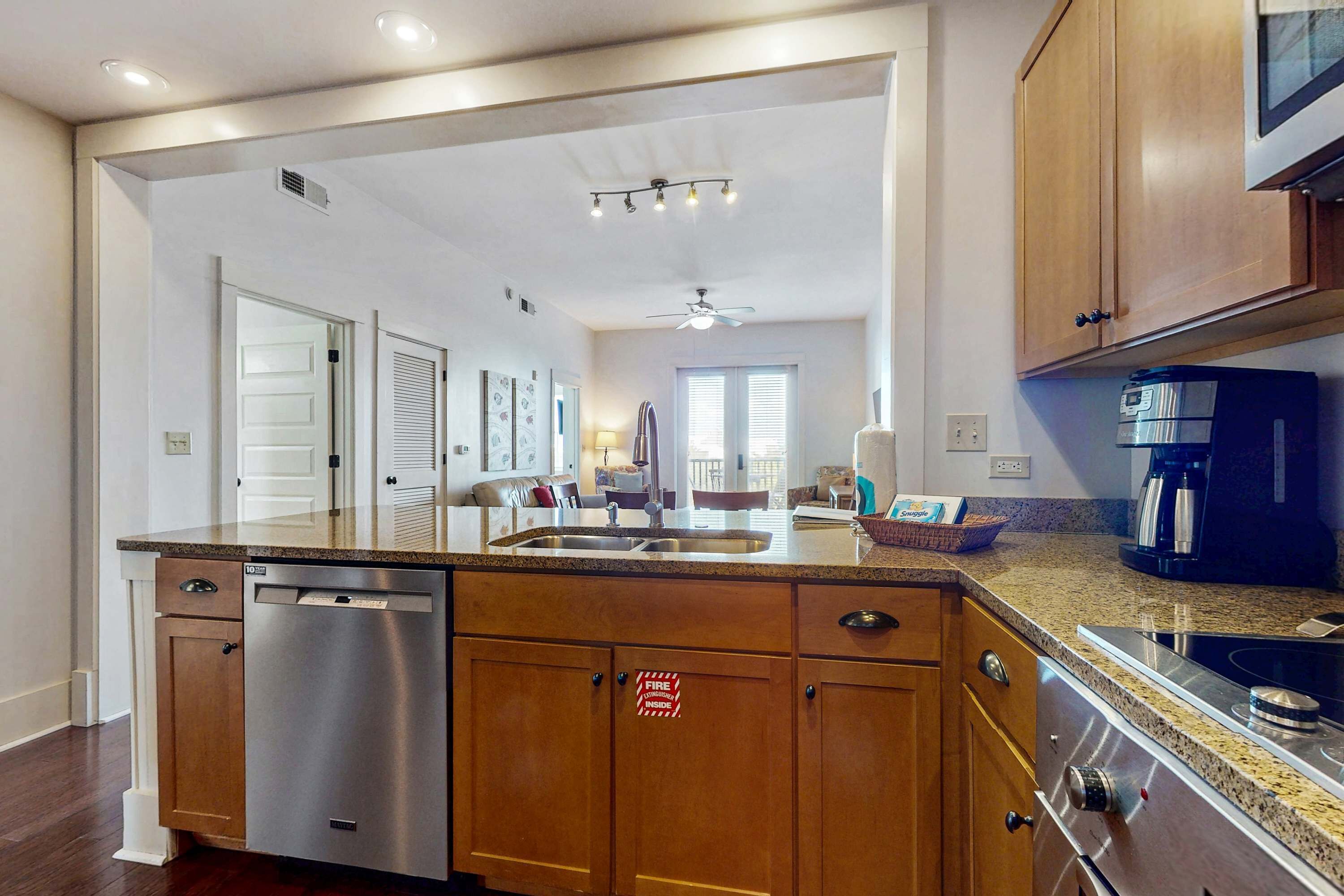 A modern kitchen with wooden cabinets, a stainless steel dishwasher, a built-in oven, and a microwave.
