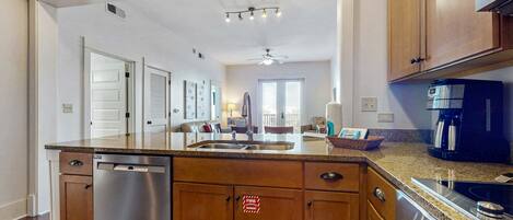 A modern kitchen with wooden cabinets, a stainless steel dishwasher, a built-in oven, and a microwave.