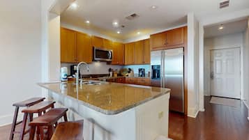 A modern kitchen with wooden cabinets, stainless steel appliances, and a granite countertop.