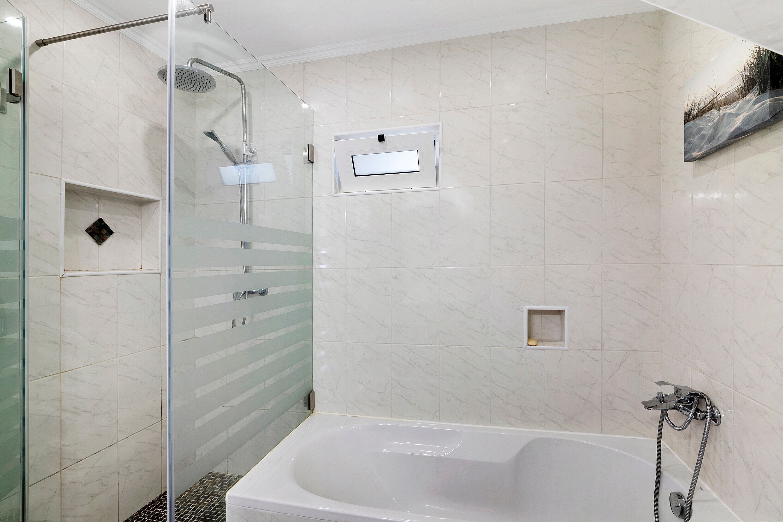 Ein modernes Badezimmer mit einer gläsernen Duschkabine, einer freistehenden Badewanne und einem wandmontierten Waschbecken.