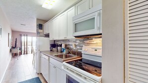 A modern kitchen with white cabinets, a microwave, an oven, and a sink. - Lovely second-floor condo w/beach access & shared outdoor pool (Panama City Beach)