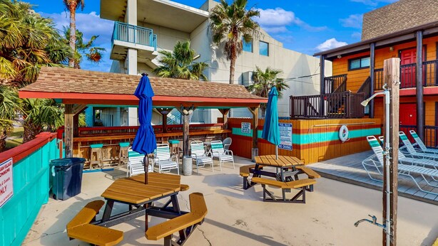 A beachside restaurant with outdoor seating, palm trees, and a pool area. - Lovely second-floor condo w/beach access & shared outdoor pool (Panama City Beach)