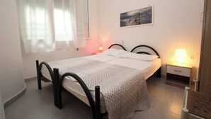 Ein Schlafzimmer mit einem Bett, zwei Nachttischen, einem Fenster mit transparenten Vorhängen und einem Wandbild.