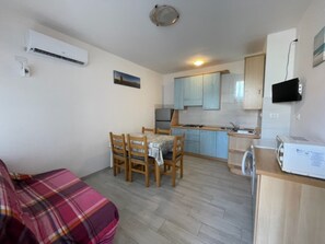A compact living space with a kitchenette, a dining area, and a sofa. - Welcoming Apartment for Families in Rosolina Mare (Rosolina)