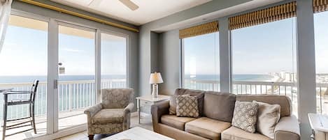 Un balcón con vista al océano, un sofá, una silla y una mesa con un plato decorativo.