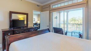 A hotel room with a large bed, a dresser, a TV, and a sliding glass door leading to an outdoor balcony. - Snowbird-friendly condo with waterfront view, WiFi, AC, access to pool, hot tub (Panama City Beach)