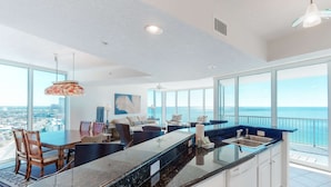 A modern kitchen with a large island, white cabinets, and a view of the ocean. - Bright Gulf-facing condo on the beach with pool & hot tub (Panama City Beach)