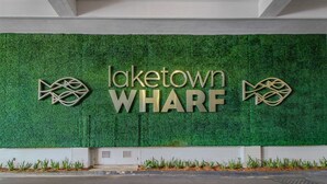 A sign for Laketown WHARF with a green wall background and decorative fish motifs. - Charming coastal condo with rooftop pool, hot tub, & washer/dryer (Panama City Beach)
