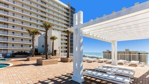 A rooftop pool area with lounge chairs and a pergola, overlooking a beach. - Charming coastal condo with rooftop pool, hot tub, & washer/dryer (Panama City Beach)
