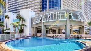 A swimming pool with lounge chairs and a building with balconies in the background. - Charming coastal condo with rooftop pool, hot tub, & washer/dryer (Panama City Beach)