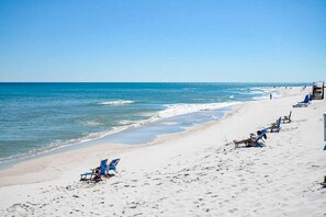 A beach with rows of blue beach chairs and umbrellas, a sandy shore, and the ocean. - Spacious fourth-floor condo - Complimentary BEACH SERVICE (Navarre Beach)