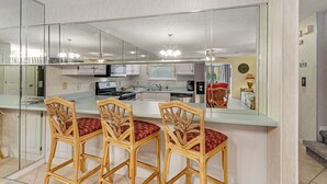 A modern kitchen with a large island, bar stools, and a mirrored backsplash. - Conveniently located condo with shared pool & tennis, on-site golf - walk to beach (Panama City Beach)
