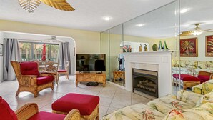 A spacious living room with a television, fireplace, and comfortable seating. - Conveniently located condo with shared pool & tennis, on-site golf - walk to beach (Panama City Beach)