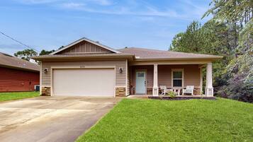 A single-story house with a garage, a front porch with two chairs, and a well-maintained lawn.