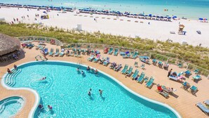 A swimming pool with lounge chairs and a beach in the background. - Light-filled beachfront condo with shared pool, hot tub & beach access (Panama City Beach)