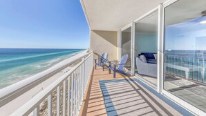 A balcony with a view of the ocean, two chairs, and a sofa. - Light-filled beachfront condo with shared pool, hot tub & beach access (Panama City Beach)