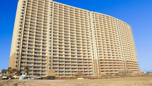 A large, multi-story hotel with a uniform facade and balconies. - Light-filled beachfront condo with shared pool, hot tub & beach access (Panama City Beach)