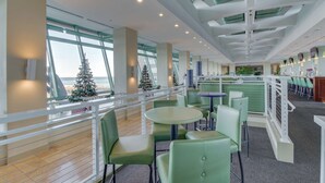 A spacious indoor area with green seating, large windows, and a view of the outside. - Light-filled beachfront condo with shared pool, hot tub & beach access (Panama City Beach)
