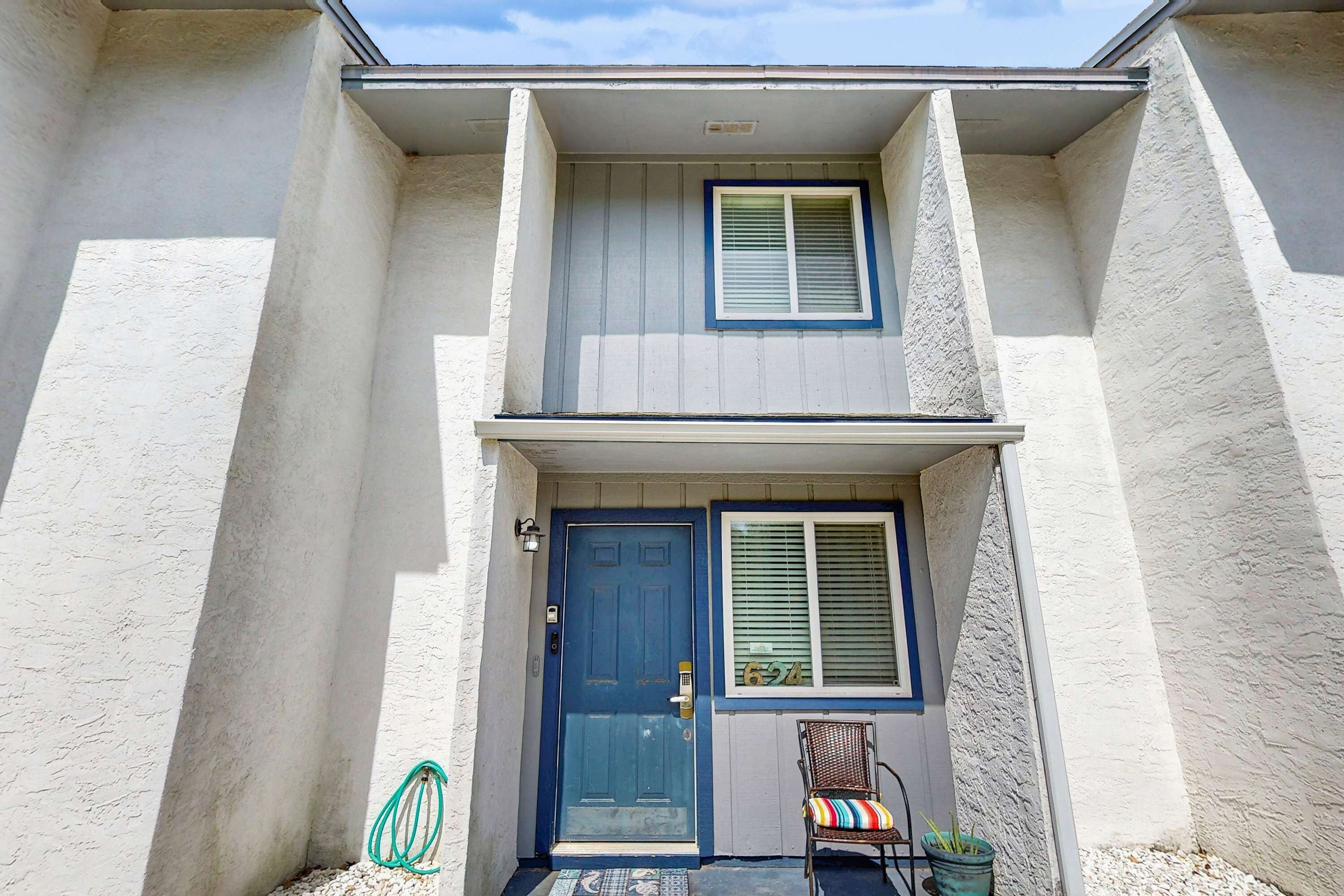 A two-story building with a blue door and a window with blinds.