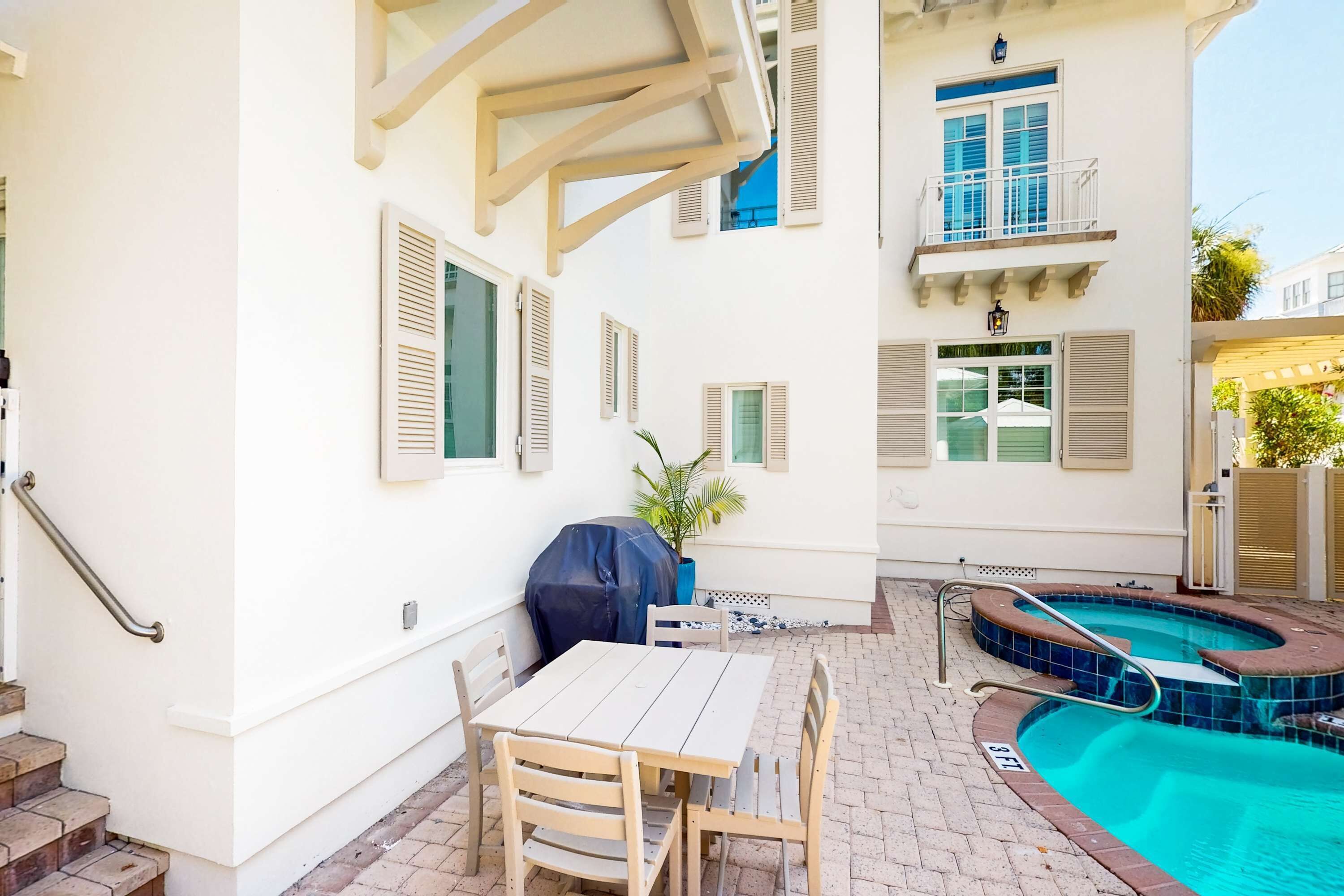 Un patio con piscina, una parrilla cubierta y una mesa con sillas.