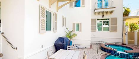 Un patio con piscina, una parrilla cubierta y una mesa con sillas.