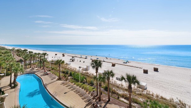 Ein Resort mit Schwimmbad, Strand und Palmen.