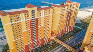 A high-rise hotel with multiple balconies, a central courtyard, and a view of the beach. - Ocean-view 10th-floor condo with balcony, heated outdoor pool, hot tub, gym, W&D (Panama City Beach)