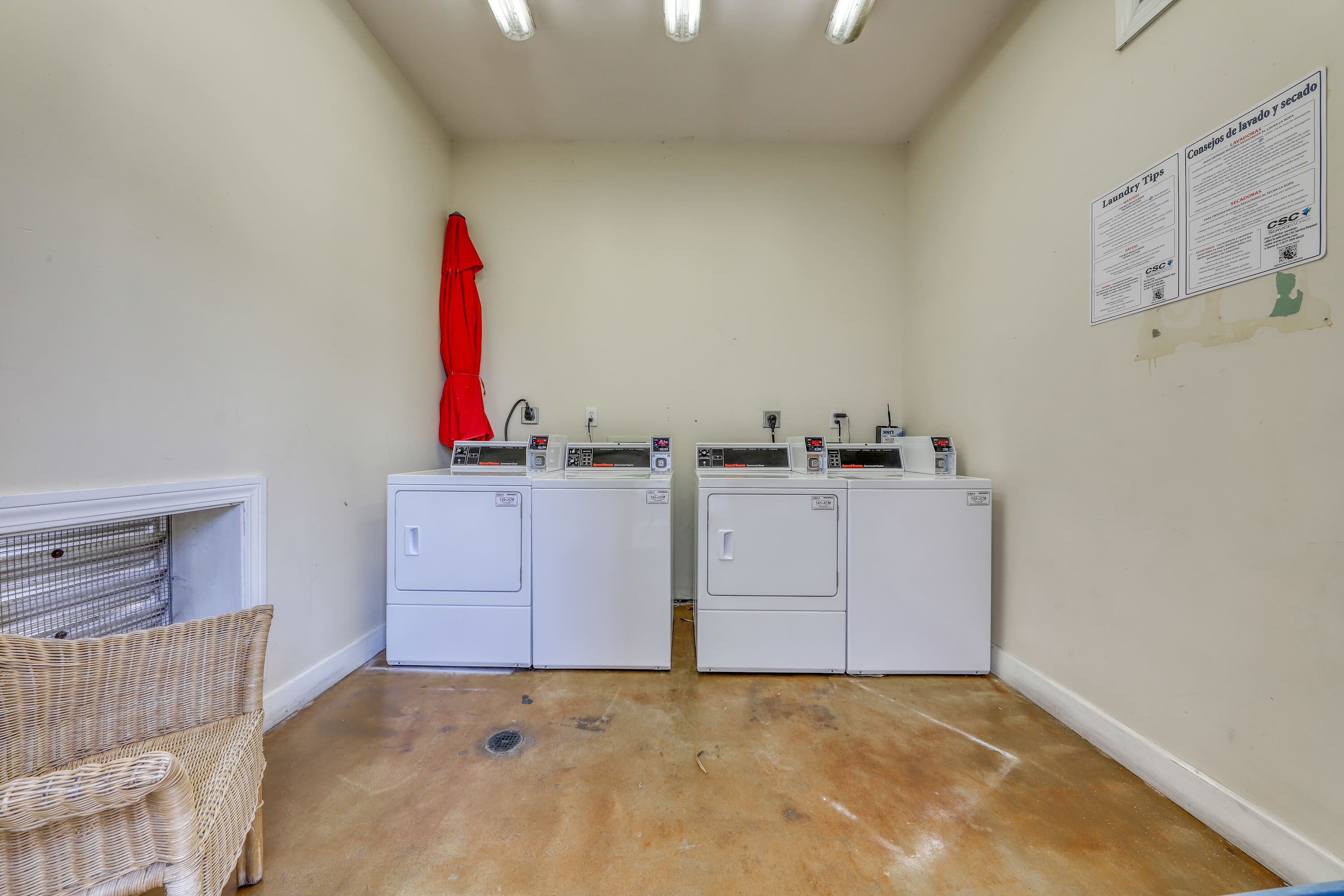 A laundry room with two washing machines, a red towel hanging, and a bulletin board with laundry tips.