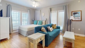 Ein Schlafzimmer mit Bett, einer Couch, einem kleinen Tisch und einem Deckenventilator.