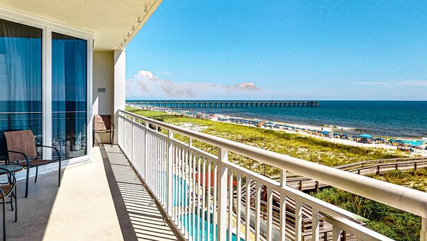A balcony with a view of a beach, a pier, and a pool area. - 3rd-Floor Gulf-Front Condo w/Balcony, Shared Hot Tub, Heated Pool, & Fast WiFi (Navarre Beach)