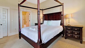 A four-poster bed with a wooden frame, a nightstand with drawers, and a lamp. - Stunning condo with washer/dryer, pool & convenient beach access (Santa Rosa Beach)
