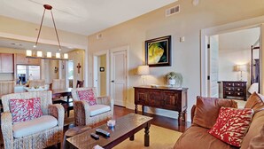 A spacious living room with wicker furniture, a brown leather sofa, and a dining area with a wooden table and chairs. - Stunning condo with washer/dryer, pool & convenient beach access (Santa Rosa Beach)